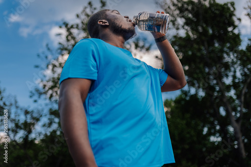 Fotografía Young black man rehydrating drinking water outdoors