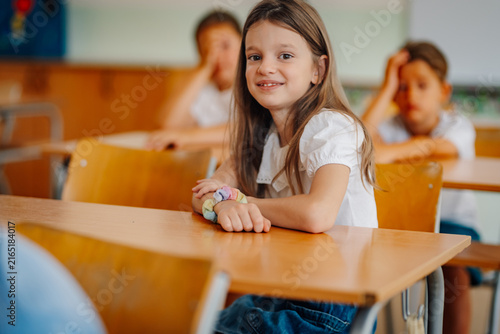 Foto Happy elementary schoolgirl smiling in classroom at desk