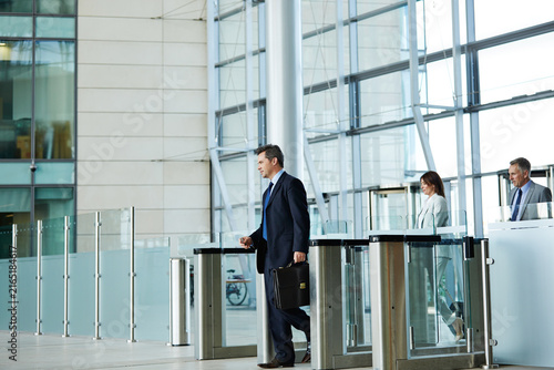 Enter, walking and business man with access to office, workplace and arrive for work or career. Corporate, workers and person with scan, id card and arrival for building security, entrance and lobby