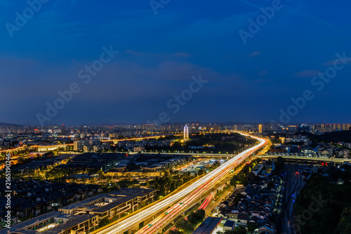 Highway light trails leading through a city at night