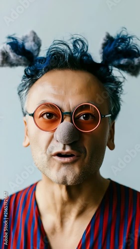 Jovial quirky clown portrait with round orange glasses and blue pompom hair accessories for fun banner and character background design