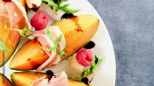Melon and prosciutto appetizer with raspberries and balsamic glaze top view
