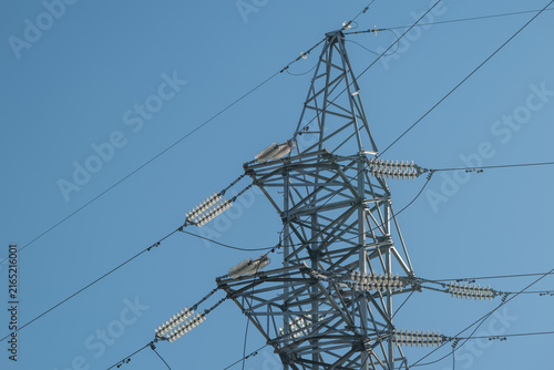 Highvoltage transmission tower stands tall against the clear blue sky with power lines stretching in multiple directions