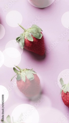 Composition of spots of light over strawberries on pink background