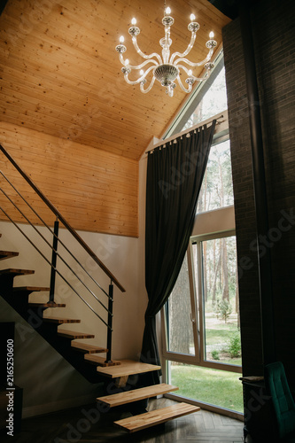 Hotel room interior with large window and curtains, stairs to the second floor, chandelier with candles for studio and wedding photography