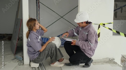 Construction inspector and worker wearing safety helmets discuss building site project plans with teamwork and focus, emphasizing uniform safety and communication indoors construction site conditions