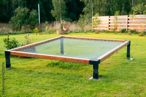 Fotografía A square trampoline frame is placed on grass in an outdoor setting
