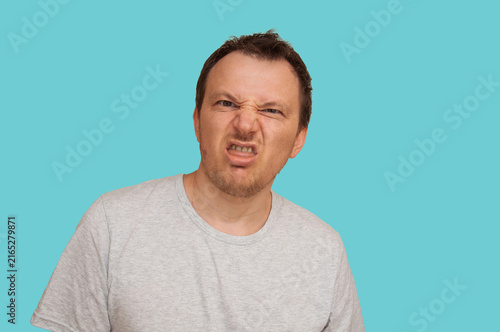 Bild auf Leinwand Man grimacing with disgust and disbelief against a bright blue background