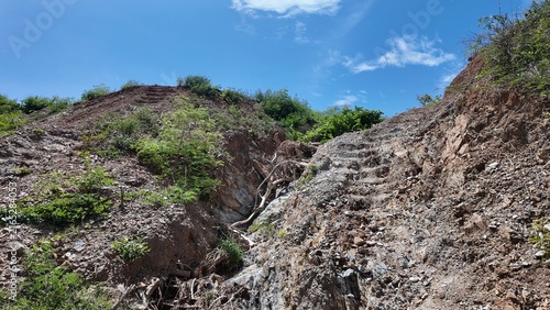 Rocky hilly landscape with dry vegetation against blue sky in summer