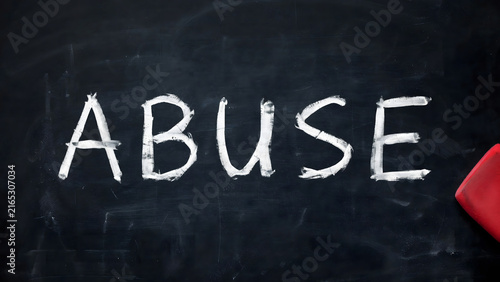 Word abuse written in chalk on a dark blackboard with a red eraser