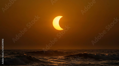 Breathtaking sunset over ocean waves with a partial solar eclipse casting golden light across the sky creating a mesmerizing view of nature's beauty