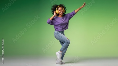 Bright, energetic young woman mid-dance pose against a solid green backdrop, perfect for lifestyle marketing, social media ads, or motivational content with a cheerful and dynamic vibe.