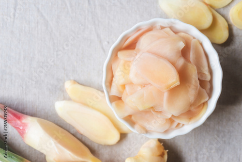 Obraz na płótnie Top view of pink pickled ginger slices in a small bowl with fresh ginger roots