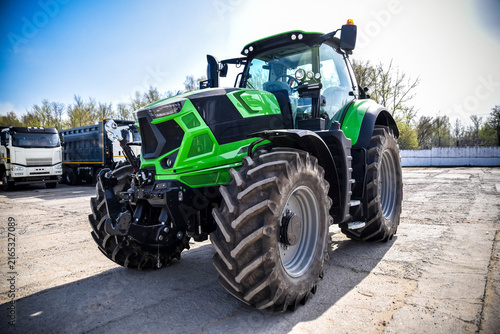 Close-up of a modern stylish green tractor. Detailed view of contemporary agricultural machinery highlighting its design, powerful construction, and advanced engineering.