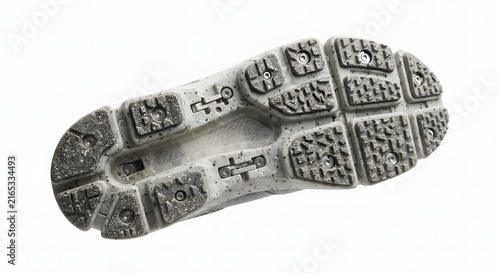 Close up view of a durable running shoe sole with metal studs for winter traction.