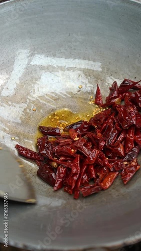 Cooking Thai chili paste with minced chicken (Nam Prik Pao Sai Gai Sub). Frying shallots, garlic, dried chilies, pounding in mortar with shrimp paste, then sautéing with minced chicken and palm sugar.