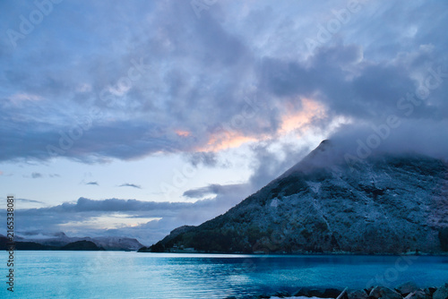 Dramatic clouds over mountains and fjord at twilight