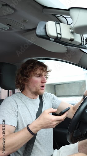 Vertical screen distracted driver looks up from his smartphone in shock when a pedestrian suddenly runs in front of the moving car creating an immediate risk of collision
