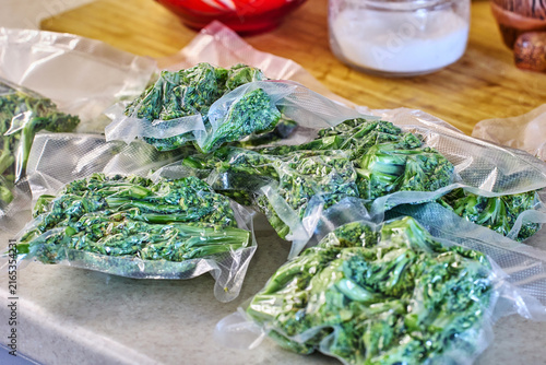 Vacuum packaging, freezing, broccoli pieces sit on kitchen countertop, presenting organized meal preparation and efficient food storage.
