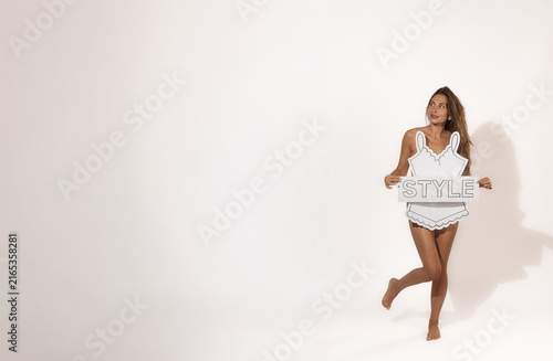 Bild auf Leinwand Woman models handmade paper lingerie while holding a STYLE sign against a bright studio background and Copy Space