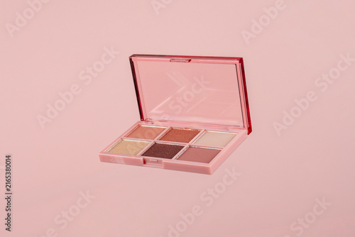 Eyeshadows palette in brown and purple shades on pink background