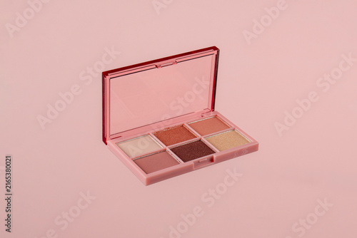 Eyeshadows palette in brown and purple shades on pink background