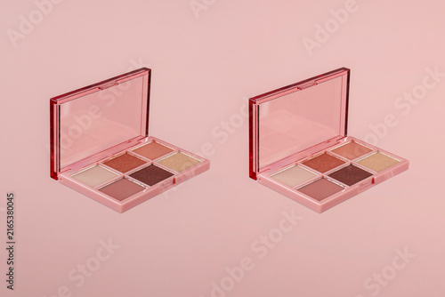 Eyeshadows palette in brown and purple shades on pink background