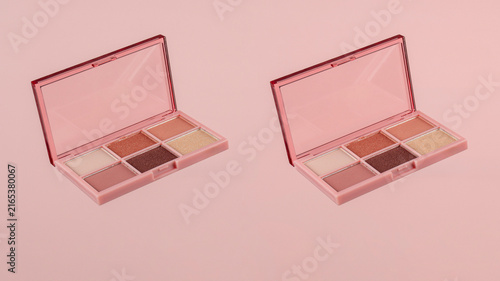 Eyeshadows palette in brown and purple shades on pink background