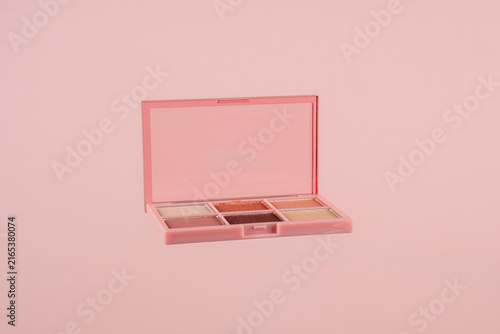 Eyeshadows palette in brown and purple shades on pink background