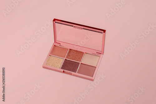 Eyeshadows palette in brown and purple shades on pink background