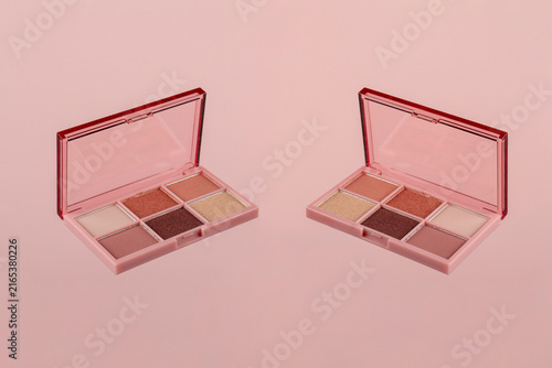 Eyeshadows palette in brown and purple shades on pink background