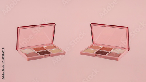 Eyeshadows palette in brown and purple shades on pink background