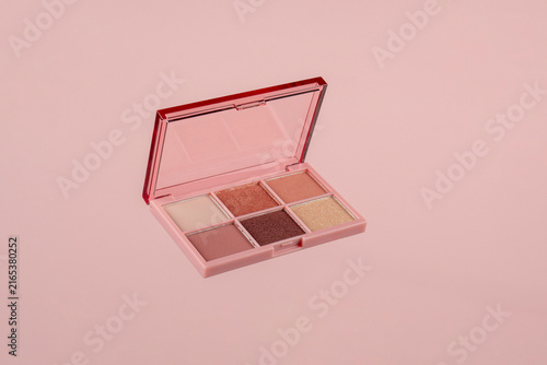 Eyeshadows palette in brown and purple shades on pink background