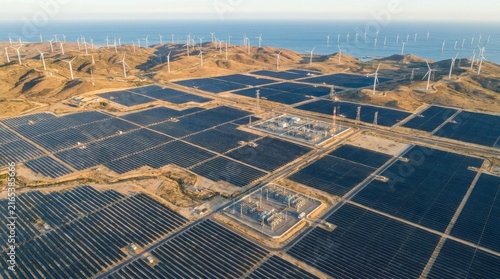 Aerial view of a large solar farm and wind turbines generating renewable energy in a landscape.