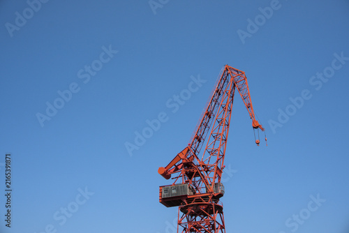 Konstfotografi Jib and machinery house of a red harbour crane against a clear blue sky