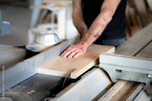 Carpenter cutting wood panel using a table saw