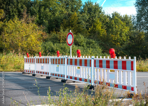 Fotografie Asphalt road is blocked with a red and white plastic barriers due to construction work