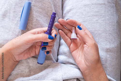 фотографія Woman's hands holding an injection pen and a needle cap, demonstrating a crucial