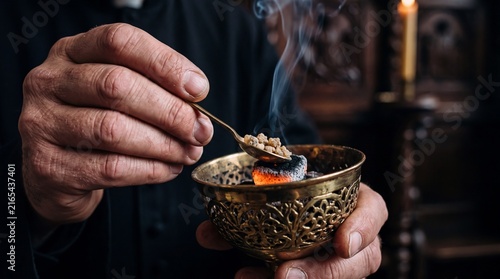 Priest putting incense resin on hot burning charcoal in brass burner inside church. Clergyman preparing fragrant smoke for traditional Christian ritual during religious service.