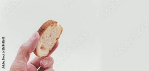 Una mano regge una fetta di pane friabile e croccante primo piano su sfondo bianco e vuoto con spazio per testo