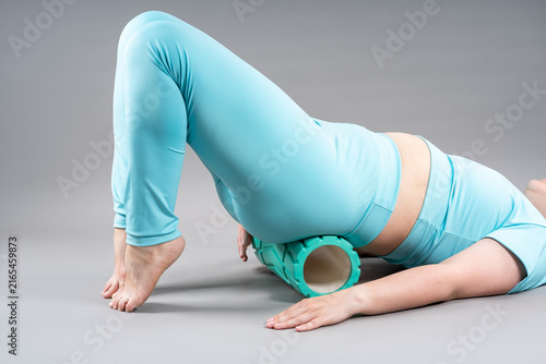 Woman doing pelvic floor, abdominal muscles, legs and lower back exercises using foam massage roller, myofascial release or pilates concept