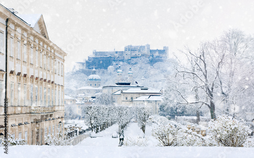 Baroque architecture of Salzburg in cold white winter landscape with falling snow and view of fortress Hohensalzburg, castle Mirabell with garden, Cathedral Dom - concept of travel - Austria Europe