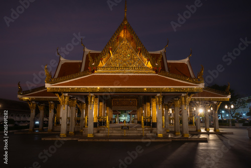 Traditional Thai Buddhist temple illuminated at night in Bangkok, Thailand, showcasing ornate architecture, golden details and spiritual atmosphere.
