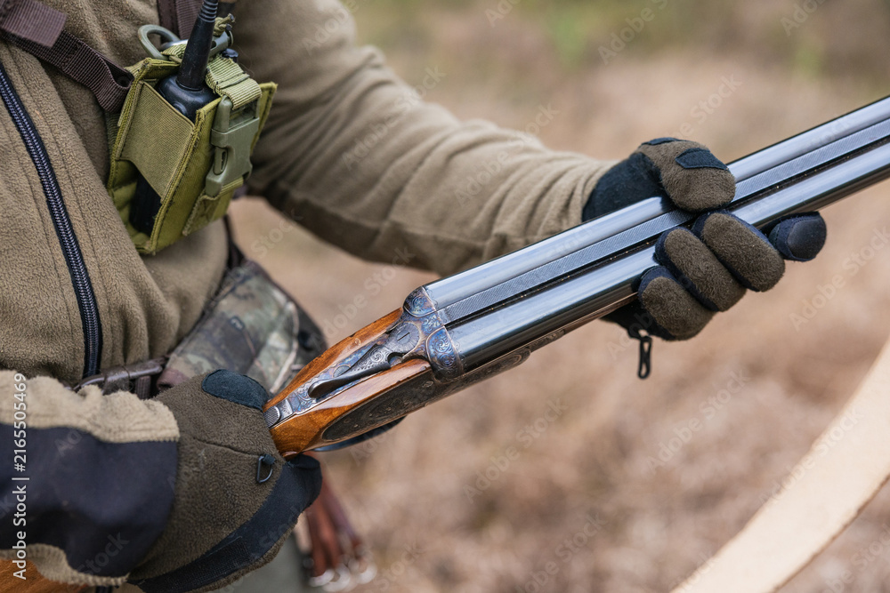 Naklejka premium Hunter handling shotgun, reloading in preparation for hunting