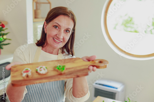 Fotografía Cheerful mom proudly displays beautifully decorated cookies cookie platter in the kitchen getting ready thanksgiving and the family christmas party smiling happily at the camera