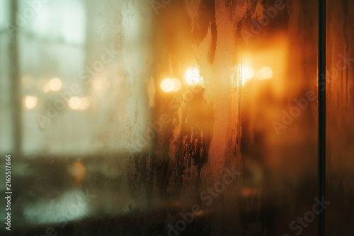 Close-up of a fogged glass surface with soft bokeh lights in the background.