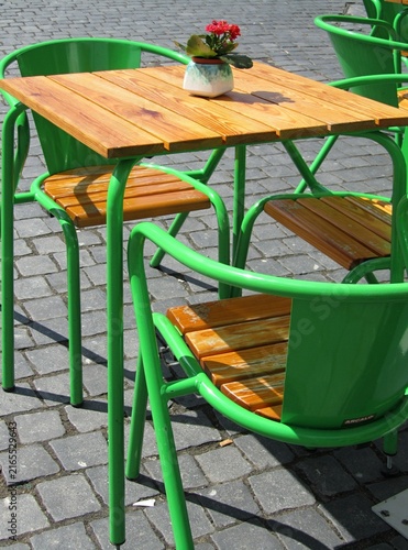Green metal chairs and wooden table inviting customers in outdoor cafe