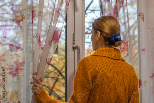 Obraz na płótnie Woman in mustard sweater looking out window, autumn view, contemplation, cozy ho