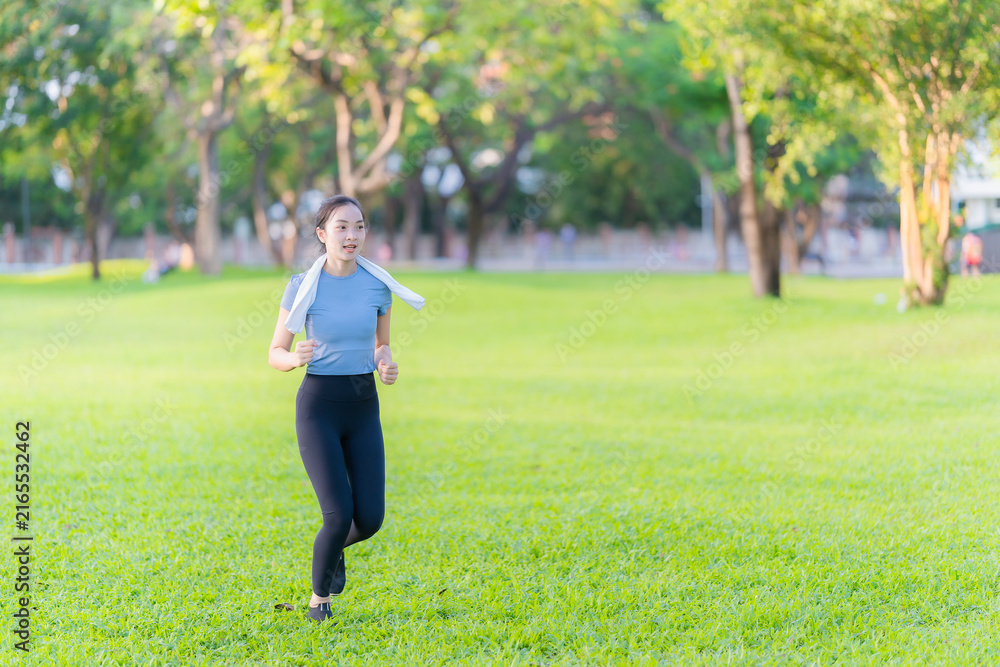 Fototapeta premium Young Asian woman in sportswear jogging and exercising outdoors in the park