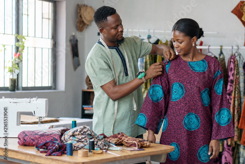 Ghanaian Tailor Fitting a Colorful Handmade Garment for a Customer inside a Contemporary Neighborhood Sewing Studio in Accra